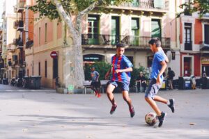 two boy's playing soccer near building during daytime
